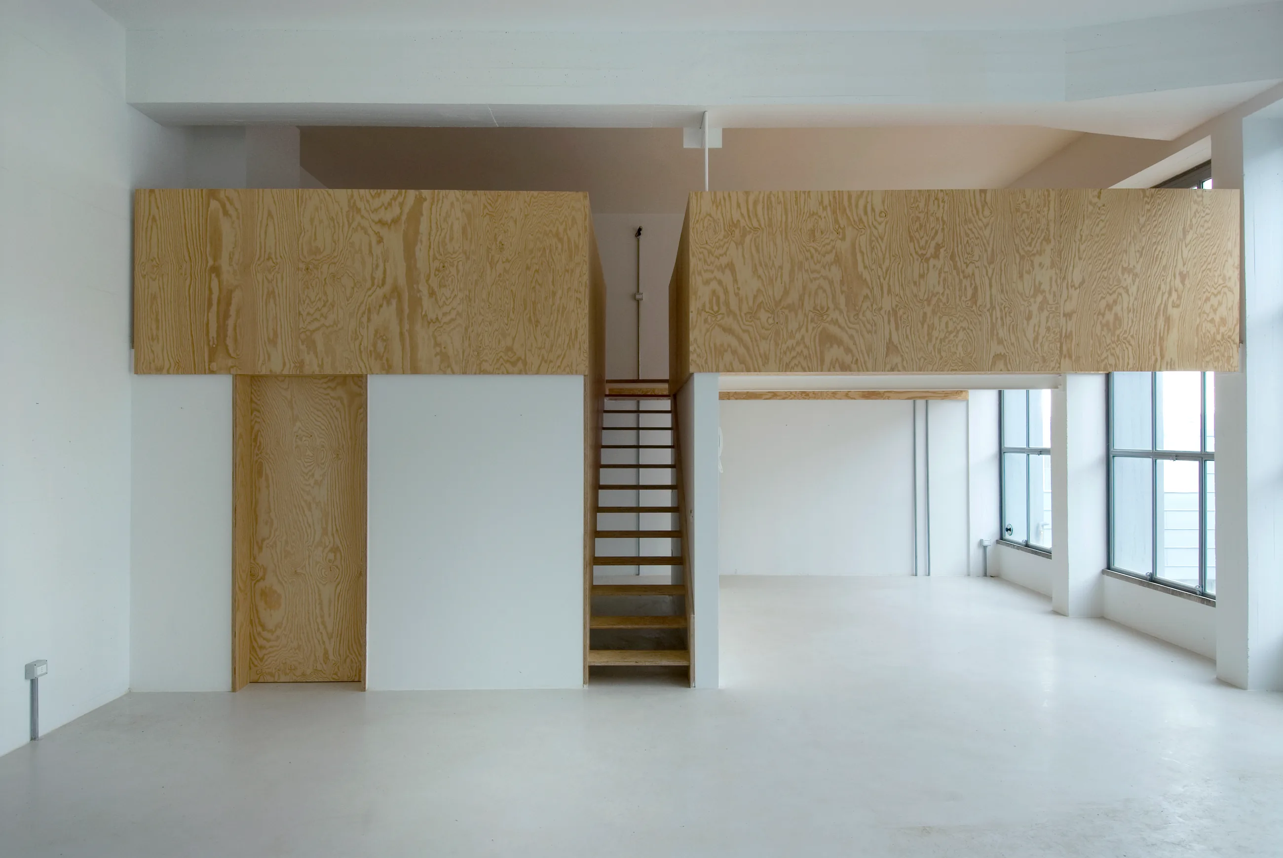 Spazio interno con soppalco, scala e ampie finestre